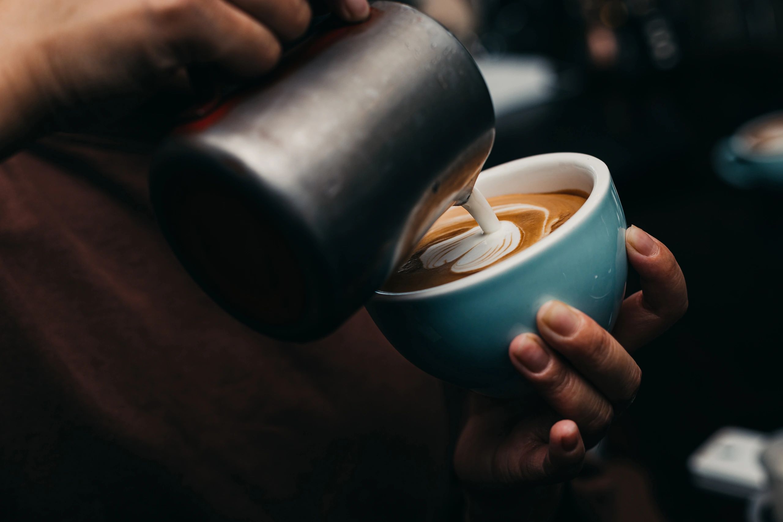 Barista pouring latte art into a cup