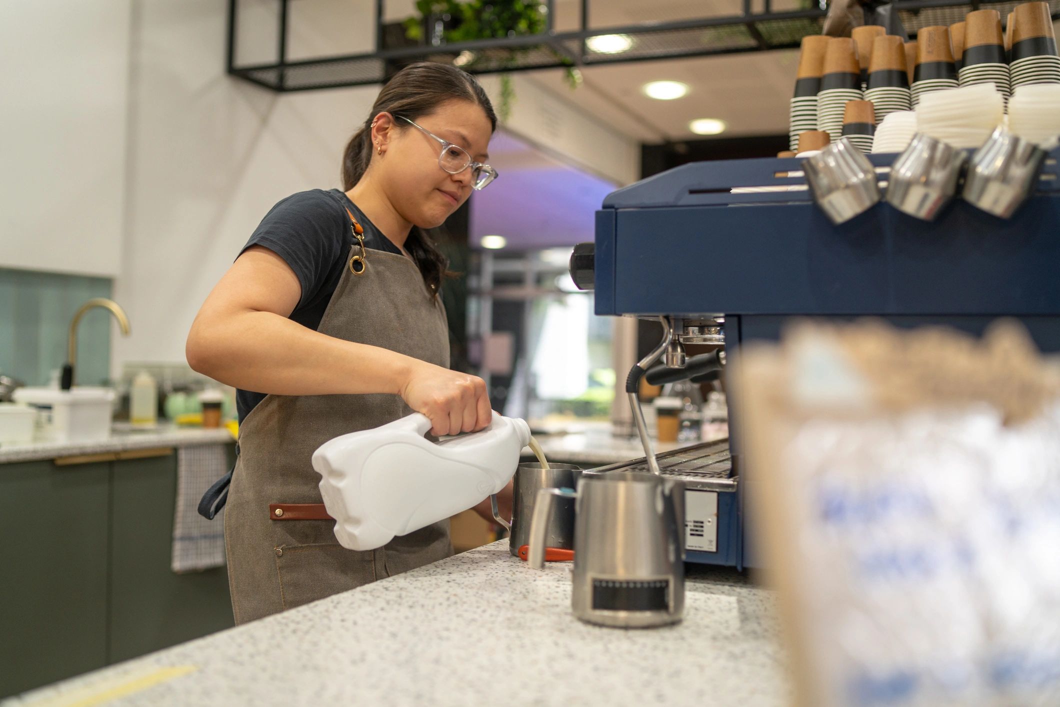 Barista steaming milk and preparing an espresso drink