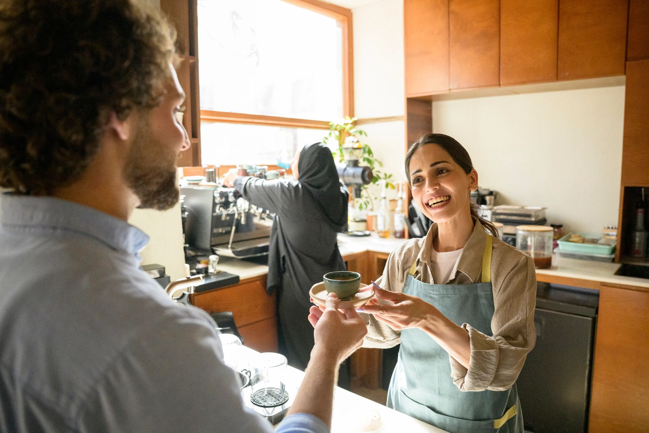 Smiling barista handing a coffee to a guest